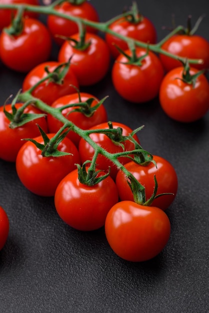 De délicieuses tomates cerises fraîches sur une brindille avec des épices et des herbes