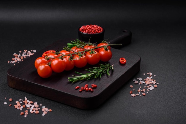 De délicieuses tomates cerises fraîches sur une brindille sur un fond de béton foncé