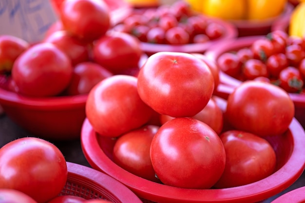 Délicieuses tomates fraîches fruits légumes aliments dans un panier en plastique rouge au marché de la tradition après-midi Séoul Corée du Sud concept de récolte gros plan