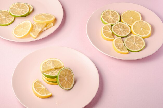 Délicieuses tranches d'agrumes au citron et au citron vert sur trois assiettes roses,