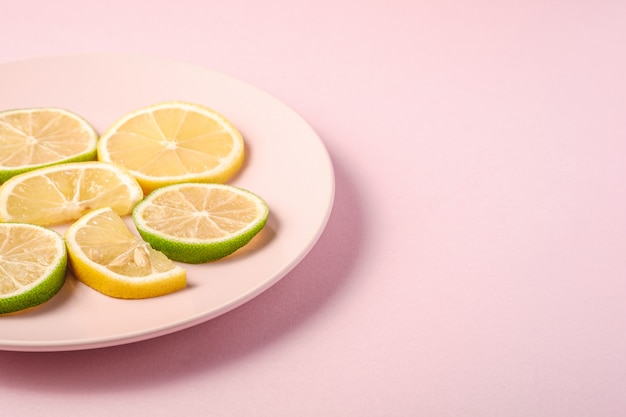 Délicieuses tranches d'agrumes de citron et de lime sur plaque rose