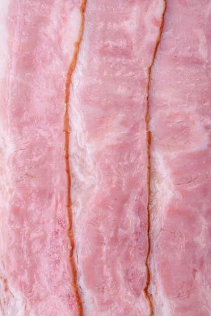 Délicieuses tranches de bacon frais avec des épices et du sel sur un fond de béton foncé