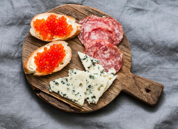 Délicieux apéritifs pour saucisses fumées au vin caviar rouge sandwichs au fromage à la crème fromage bleu sur une planche à découper en bois