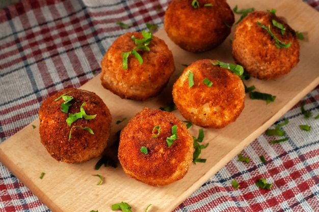 Délicieux arancini italien chaud - boules de riz farcies au fromage sur une planche sur une vieille table en bois