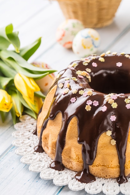 Délicieux babovka de gâteau de vacances slovaque et tchèque avec glaçage au chocolat. Décorations de Pâques - tulipes printanières et œufs.