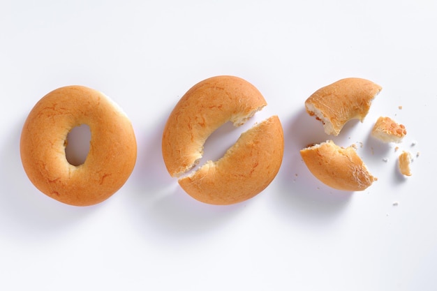 Délicieux bagels frais entiers et cassés sur fond blanc vue de dessus