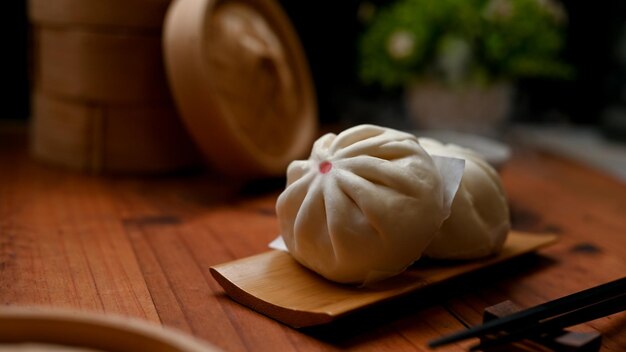 Délicieux baozi chinois ou petits pains de porc cuits à la vapeur sur une assiette en bois