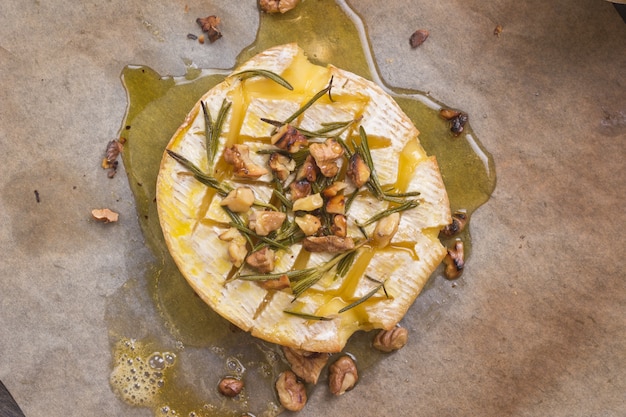 Délicieux beau camembert cuit au four avec du miel, des noix, des herbes et des poires