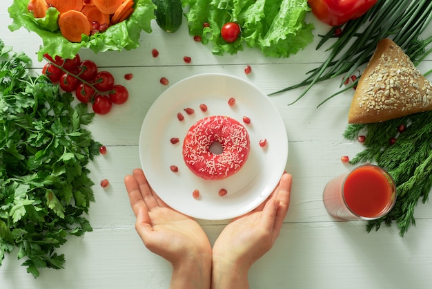 Un délicieux beignet se trouve sur une assiette et mange pour le manger. Problèmes de bonne nutrition et concept de choisir entre des aliments sains et non sains