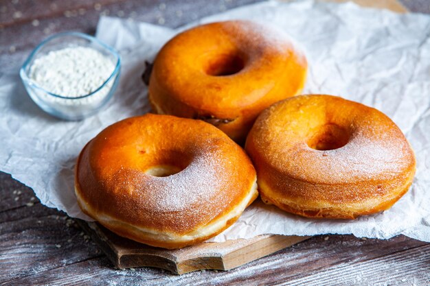 Délicieux beignets avec du sucre en poudre sur table en bois