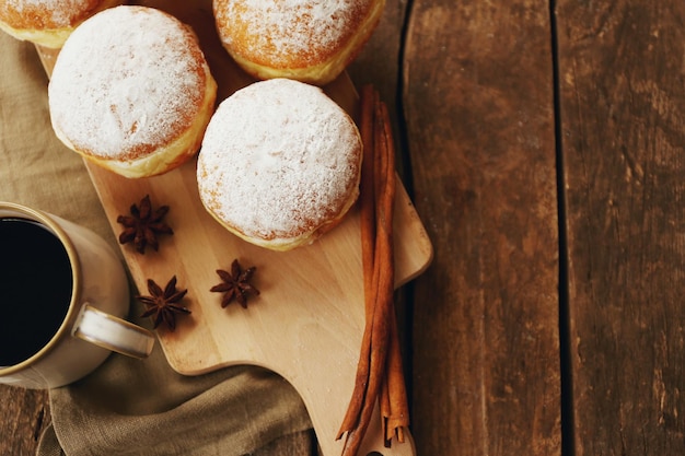 Délicieux beignets sucrés aux épices et tasse de café sur fond de bois