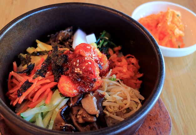 Délicieux Bibimbap, un riz mélangé traditionnel coréen avec de la viande et des légumes assortis dans un bol en pierre chaude