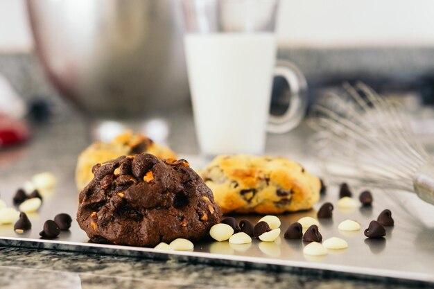 Photo délicieux biscuit aux pépites de chocolat avec des pépites autour et un verre de lait