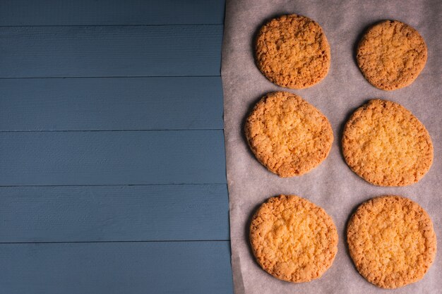 De délicieux biscuits faits maison sur du papier sulfurisé sur une table en bois bleue