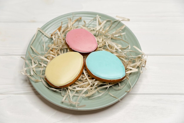 Délicieux biscuits avec glaçure colorée sur une assiette en bois blanc