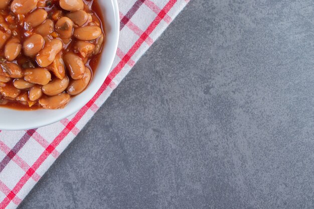 Délicieux bol de fèves au lard sur un torchon sur la surface bleue