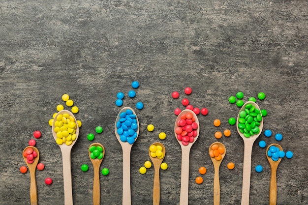 délicieux bonbons sucrés colorés sur cuillère sur fond coloré décor de confiserie vue supérieure avec espace de copie