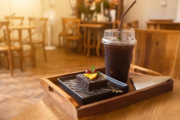 De délicieux brownies au chocolat et à l'orange au chocolat frais faits maison et du café glacé Americano ou du café noir dans un bureau en bois