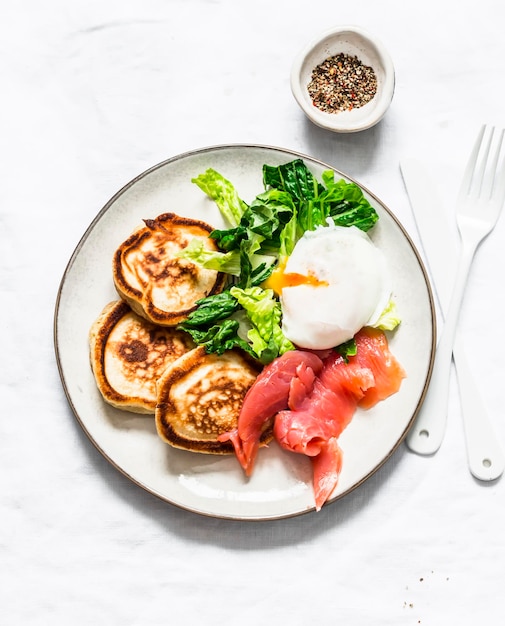 Délicieux brunch sain oeuf poché saumon fumé salade verte et crêpes salées sur fond clair vue de dessus