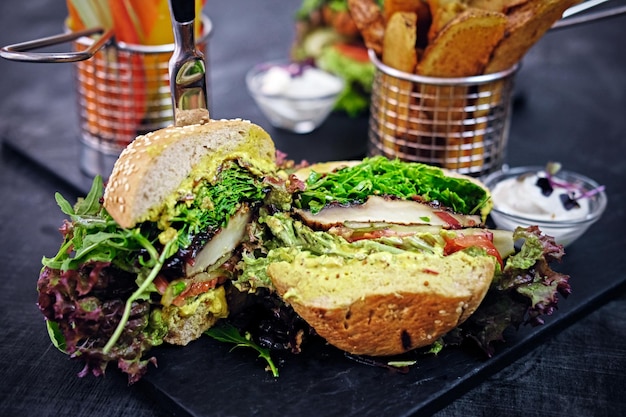 Délicieux burger, frites avec salade sur une table.