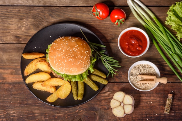 Délicieux burger maison grillé. Délicieux hamburgers grillés. Burger de boeuf artisanal et frites sur table en bois