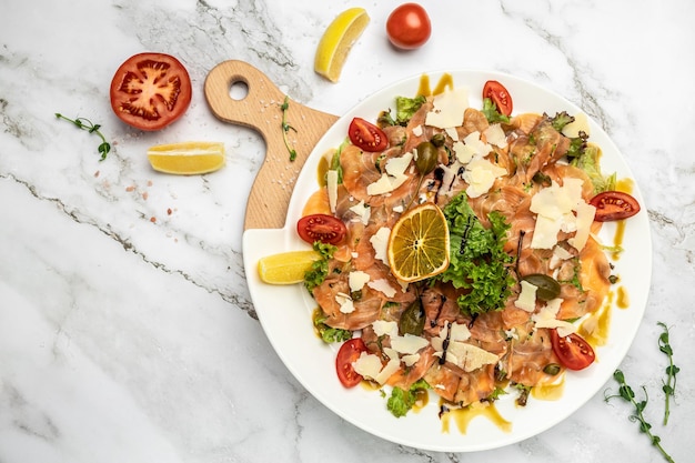 Délicieux carpaccio de saumon servi avec câpres, parmesan et tomates cerises. bannière, menu, lieu de recette pour le texte, vue de dessus.