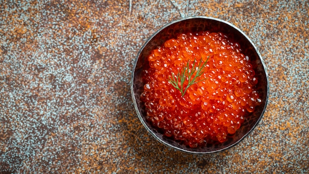 Photo délicieux caviar rouge dans un bol noir.