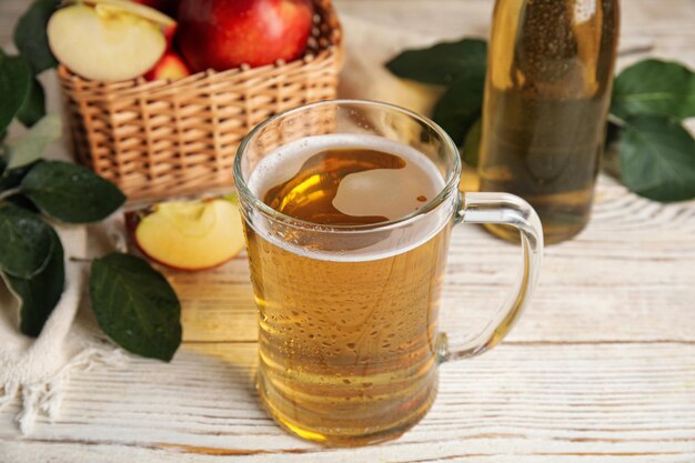 Délicieux cidre de pomme dans une tasse en verre sur une table en bois blanc