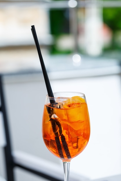 Délicieux cocktail d'aperol d'été léger et rafraîchissant avec de la glace et de l'orange dans un gobelet en verre, boisson gazeuse avec des pailles pour les filles
