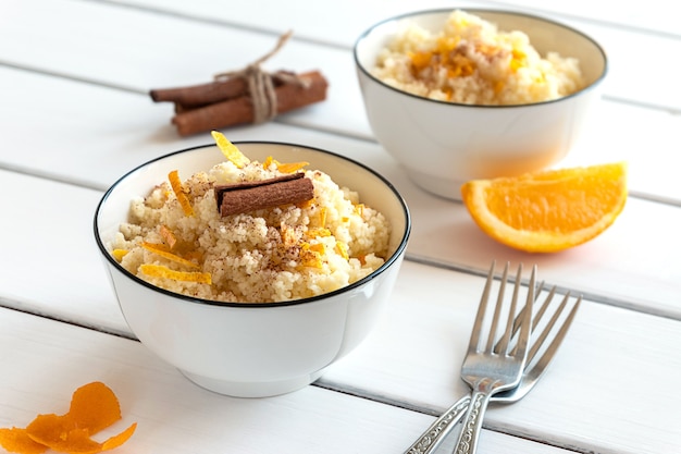 Délicieux couscous maison aux oranges et cannelle sur fond de bois rustique. Nourriture végétalienne savoureuse.