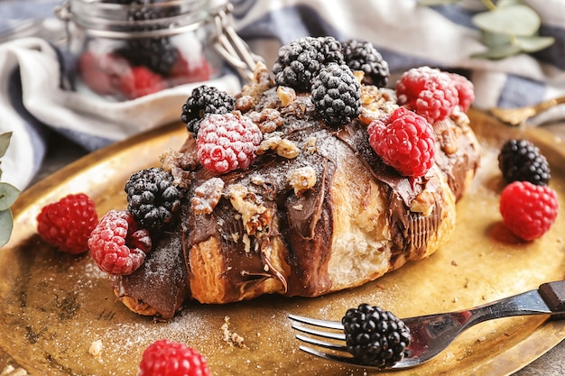 Délicieux croissant avec pâte de chocolat, noix et baies sur plateau en métal