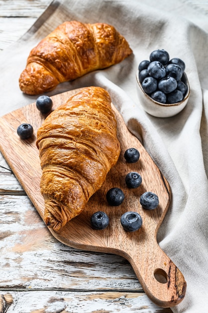 Délicieux croissants au beurre aux myrtilles sur la vieille table en bois. Fond blanc. Vue de dessus.