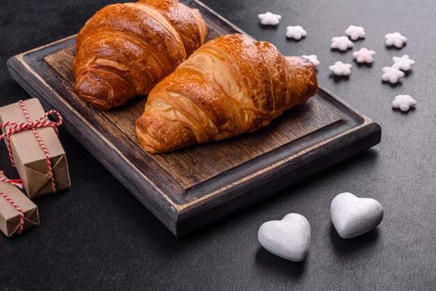 Délicieux croissants frais et croustillants sur fond de béton foncé. Petit déjeuner savoureux