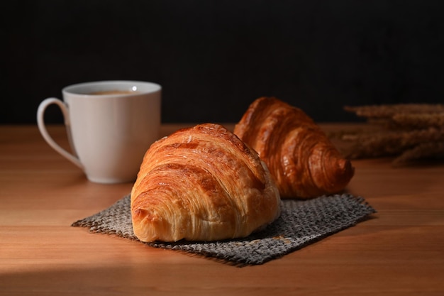 Délicieux croissants frais et tasse de café sur une table en bois pour le petit-déjeuner fait maison