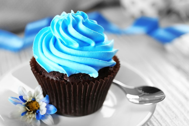 Délicieux cupcake au chocolat avec de la crème bleue sur une table en bois décorée se bouchent