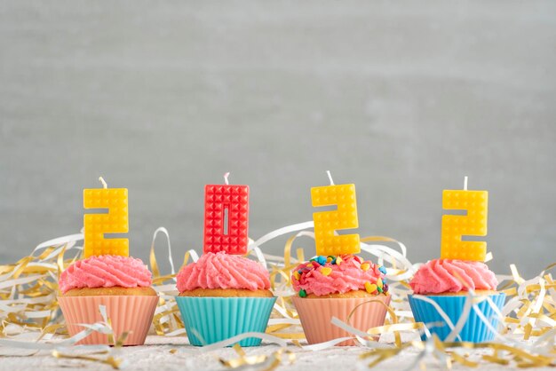 Délicieux cupcakes décorés de bougies sous forme de nombres 2022 sur fond gris. Célébration du Nouvel An.