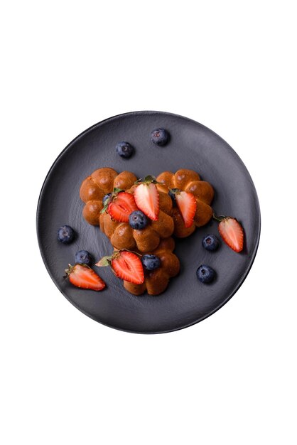 Délicieux cupcakes ou muffins aux raisins secs et aux noix, fraises et bleuets sur une assiette en céramique sur une table en béton texturé