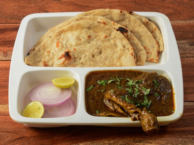 Délicieux curry de poulet indien avec du pain naan servi sur une table en bois rustique mise au point sélective