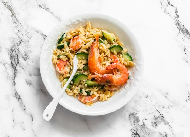 Délicieux déjeuner méditerranéen orzotto crémeux aux crevettes et courgettes sur une vue de dessus de table en marbre