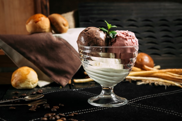 Délicieux délicieux chocolat et crème glacée aux fraises avec des feuilles de menthe sur le fond en bois, horizontal, vue latérale