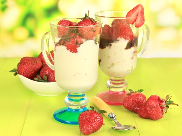 Délicieux desserts aux fraises dans un vase en verre sur une table en bois sur fond naturel
