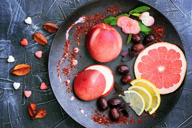 Délicieux desserts à la pêche sur l'assiette noire décorée de fruits.