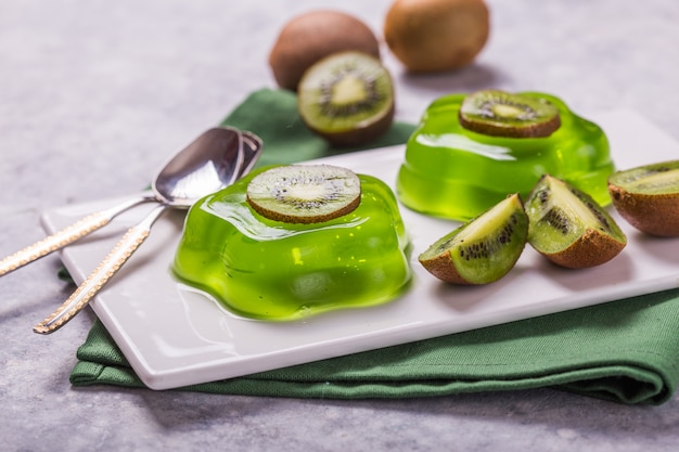 Délicieux deux gelée verte fraîche avec des tranches de kiwi sur table en béton