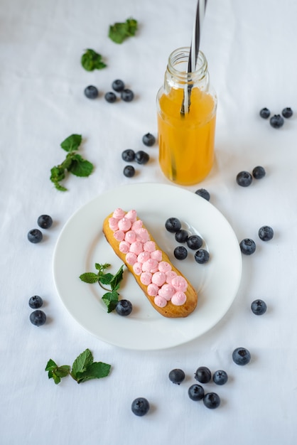 Délicieux éclairs faits maison sur une nappe blanche. Les myrtilles sont dispersées partout.