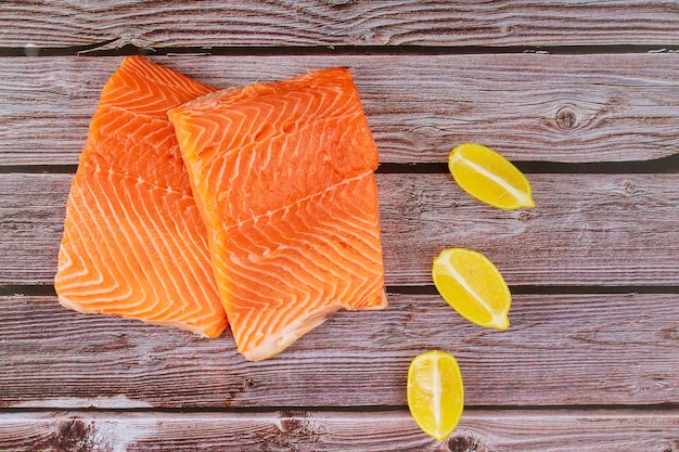 Délicieux filet de poisson saumon cru avec des tranches de citron sur une planche de bois