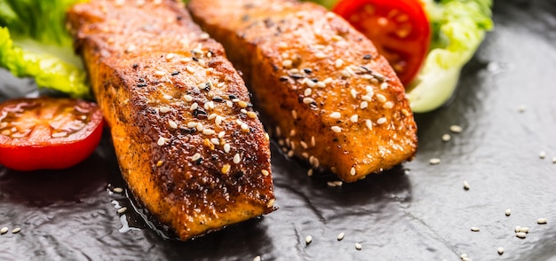 Délicieux filets de saumon rôtis grillés ou steaks avec tomates au sésame et salade de laitue.