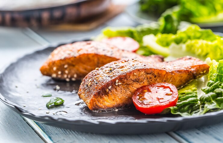 Photo délicieux filets de saumon rôtis grillés ou steaks avec tomates au sésame et salade de laitue.