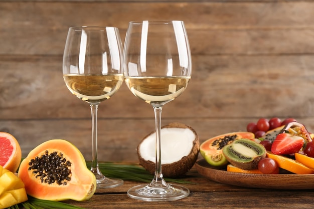 Délicieux fruits exotiques et verres de vin sur table en bois