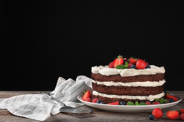 Délicieux gâteau au chocolat avec des baies sur la table sur fond noir