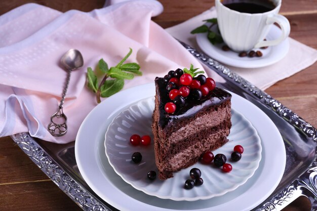 Délicieux gâteau au chocolat avec des baies et une tasse de café sur la table se bouchent